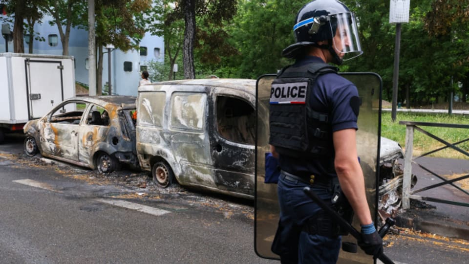Ein französischer Polizeibeamter steht neben ausgebrannten Autos in der Pariser Vorstadt Nanterre.