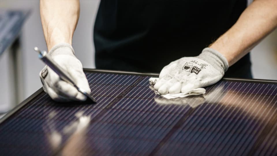 Ein Mitarbeiter von Meyer Burger entfernt überschüssiges Silizium von der Oberfläche eines Solarmoduls.