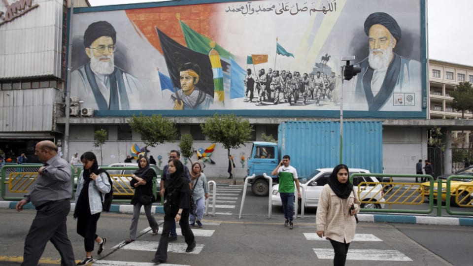Iranerinnen und Iraner laufen neben einem Bild des iranischen Obersten Führers Ayatollah Ali Khamenei vorbei.
