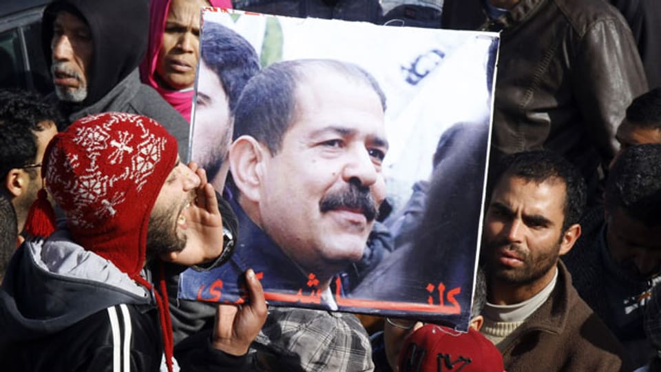 Tunesier halten ein Bild des ermordeten Oppositionspolitikers Chokri Belaïd während der Beerdigung.