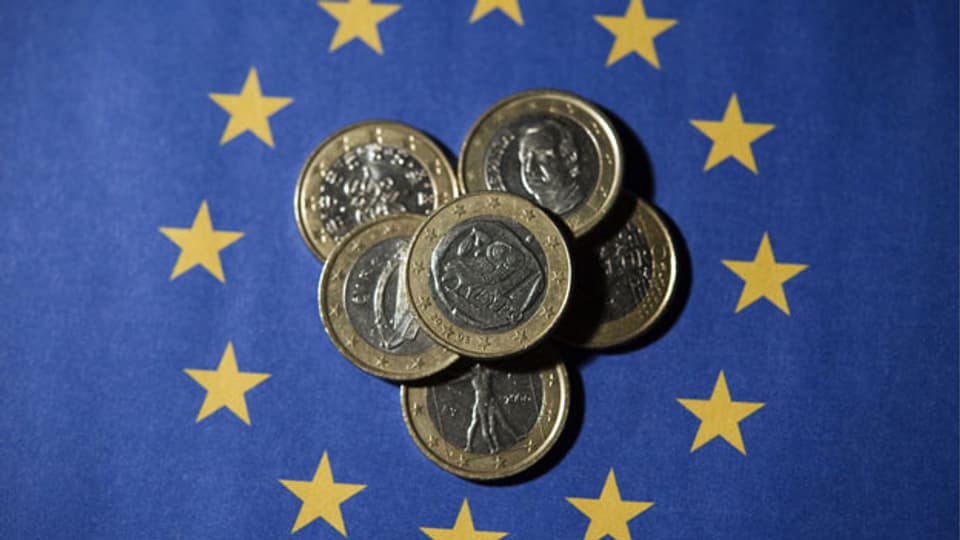 Ein-Euro-Münzen auf der EU-Flagge.