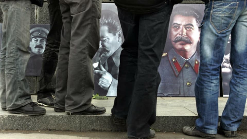 Passanten in Russland betrachten Bilder von Josef Stalin.
