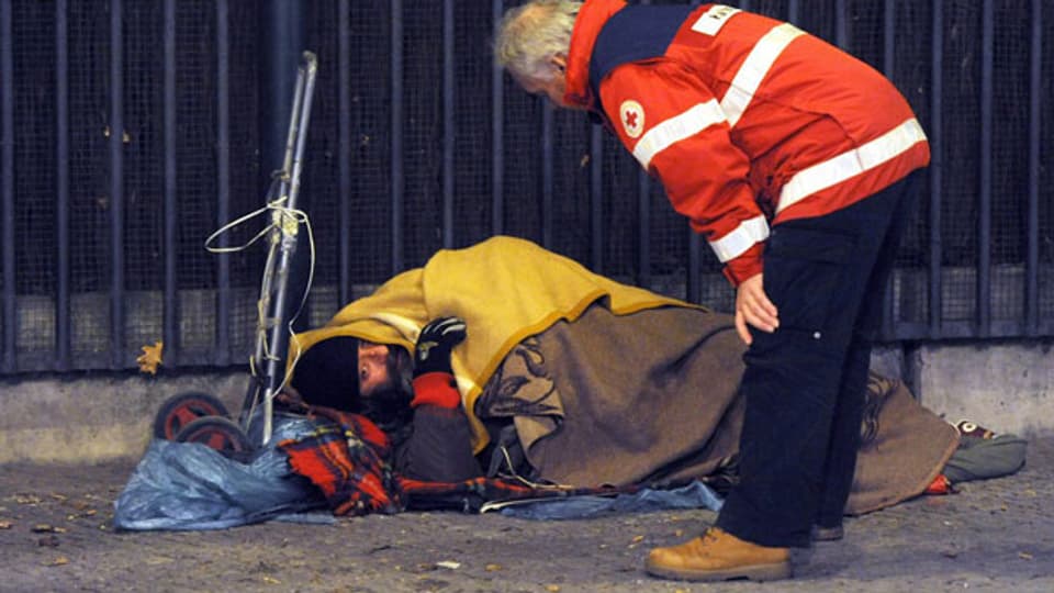 In Deutschland hat nicht jeder ein Dach über dem Kopf. Ein Rotkreuz-Mitarbeiter spricht mit einem Obdachlosen in Berlin.