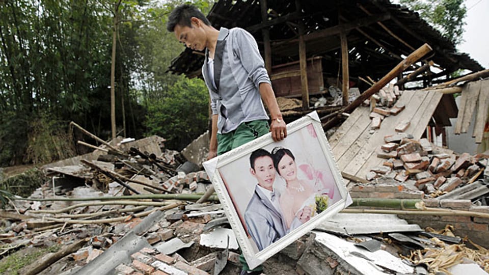 Ein Mann in der südwestchineischen Provinz Sichuan rettet ein Hochzeitsbild aus den Trümmern seines Hauses.
