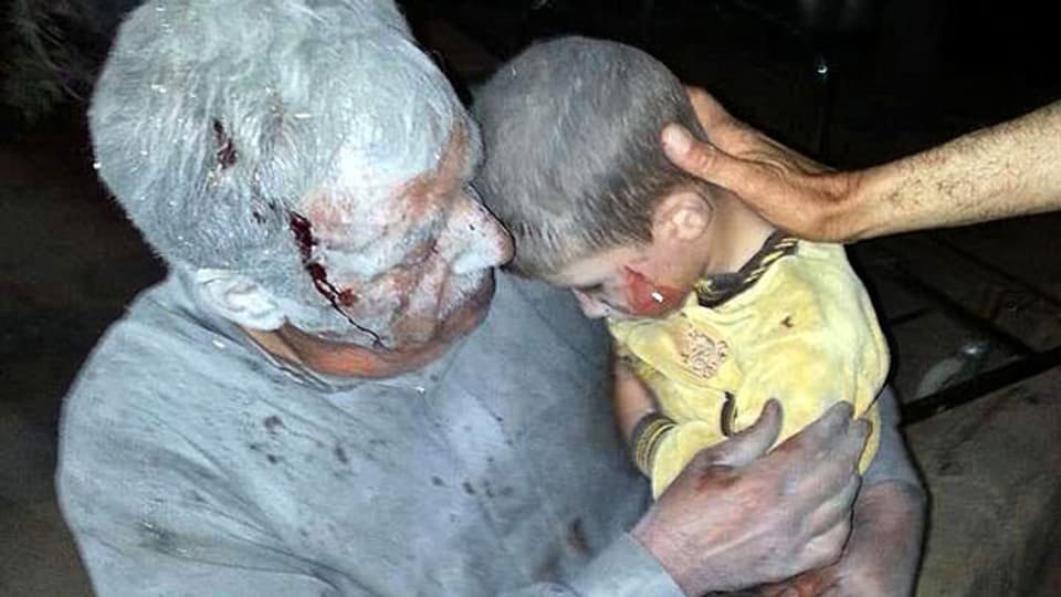 Ein verwundeter syrischer Mann hält seinen verletzten Sohn nach einem Luftangriff auf Saraqeb,Syrien. Die USA befürchten, dass chemische Waffen verwendet wurden.