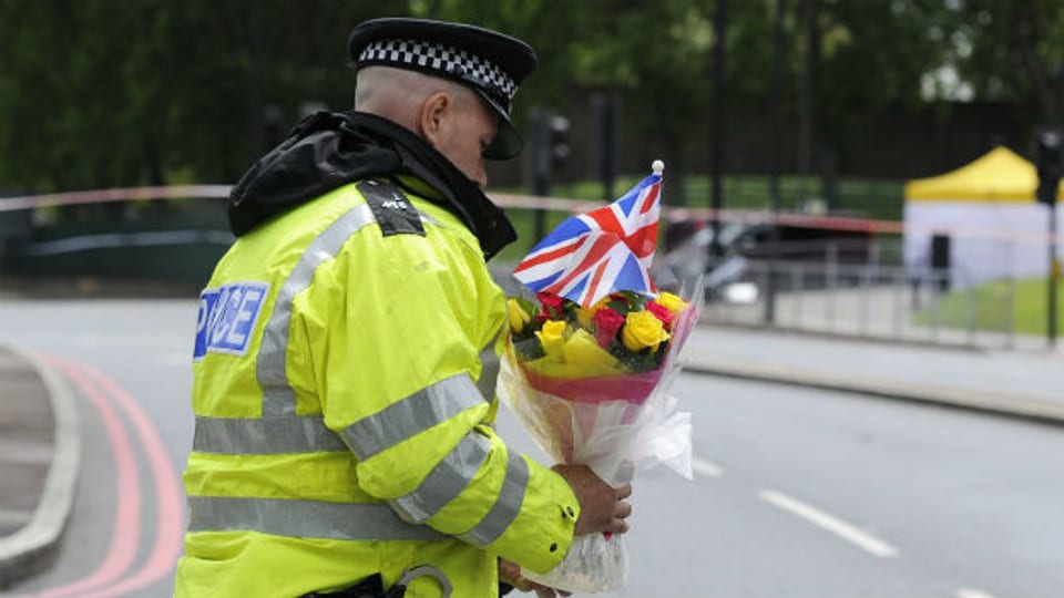 Ein Polizist bringt Blumen in die John Wilson Street, wo sich die Tat ereignet hat.