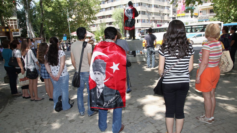 Demonstranten, einer trägt eine Nationalflagge mit einem Bild von der Türkei Gründer Kemal Atatürk, in einem stillen Protest in Kugulu Park in Ankara, Türkei, Mittwoch, 19. Juni 2013 stehen. Still und leise: Nach Wochen der Konfrontation mit der Polizei haben türkische Demonstranten eine neue Form des Widerstands gefunden.
