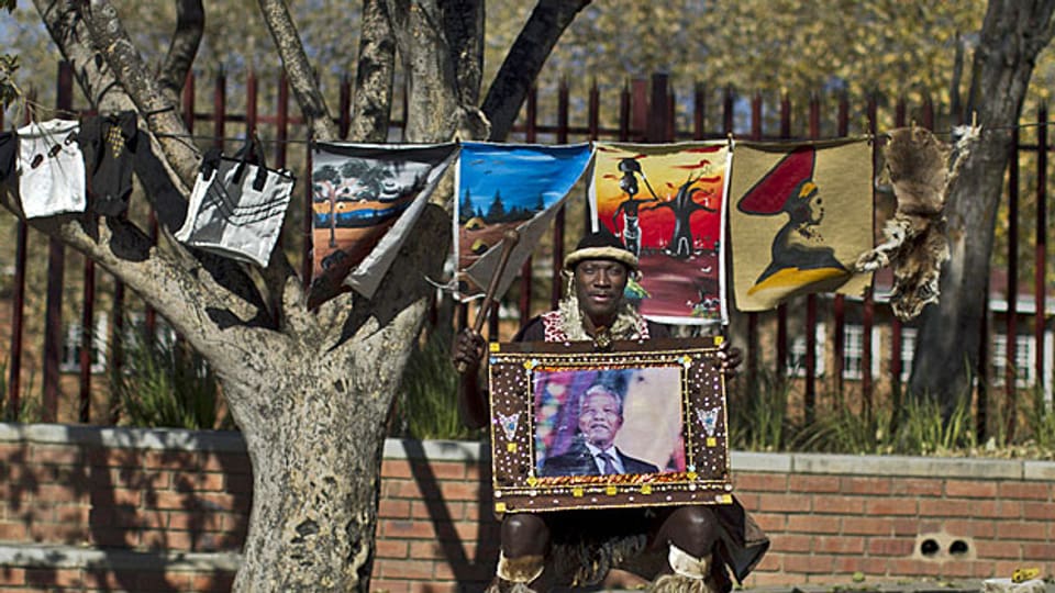 Ein Bewohner Sowetos posiert mit einem Footo von Nelson Mandela, am 1. Juli 2013.