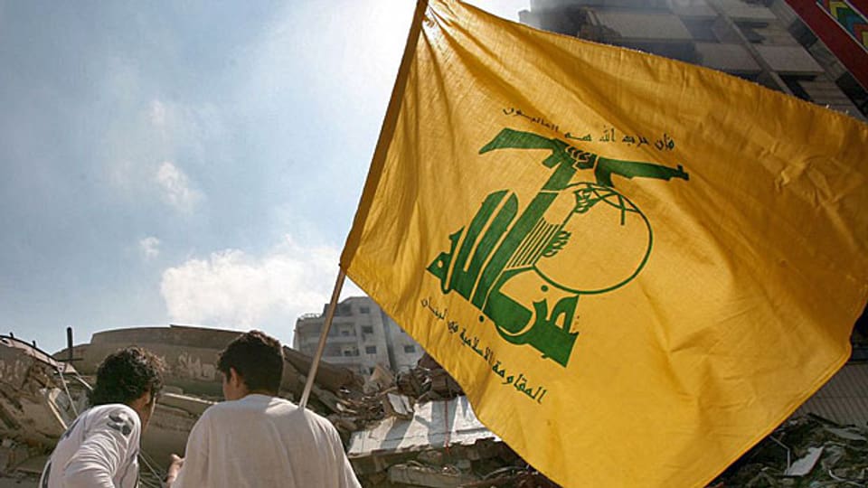 Zwei junge Männder mit einer Flagge der Hisbollah.