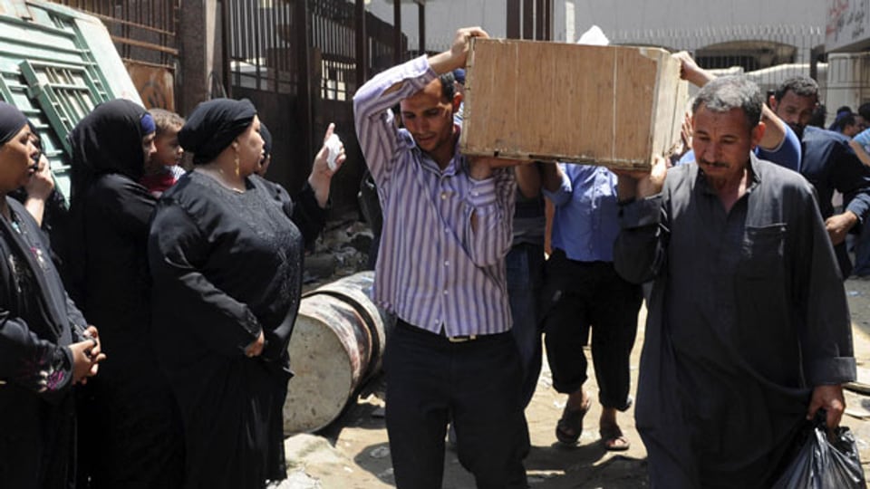Die Liste der Opfer wird länger; die Gewalt artet immer mehr aus. Ägypter tragen einen Sarg von der Leichenhalle Zenhoum zur Beerdigung.