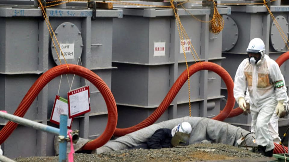 Ein Mitarbeiter in Schutzkleidung arbeitet rund um Tanks mit radioaktivem Wasser am AKW Fukushima am 12. Juni 2013. Über 300 000 Liter radioaktives Wasser sind ausgeflossen und versickern in Boden.