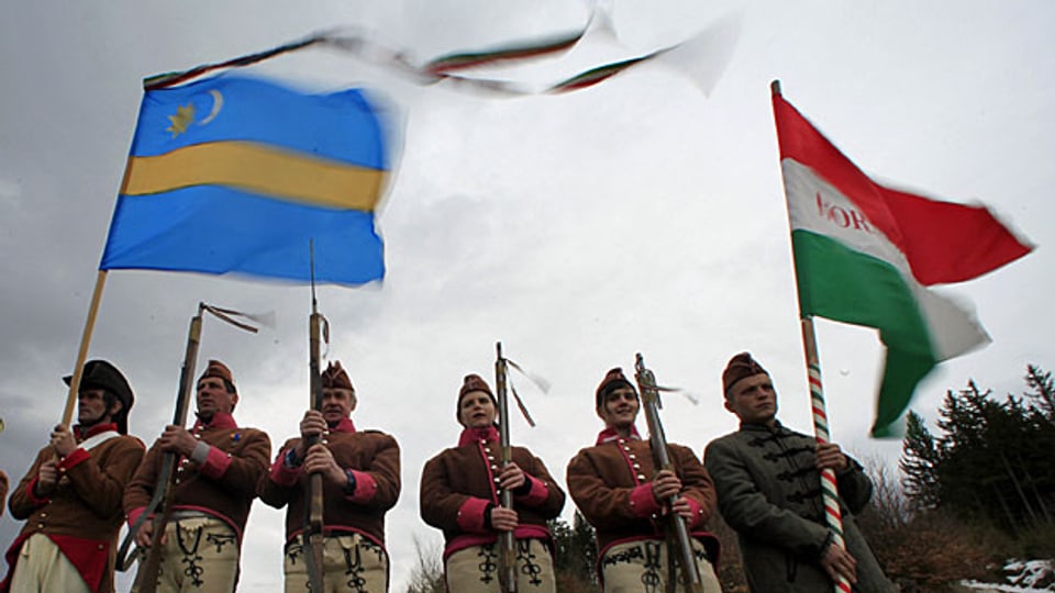 Ethnische Ungarn in traditionellen Uniformen mit der ungarischen und der Szekler-Flagge - in Rumänien.