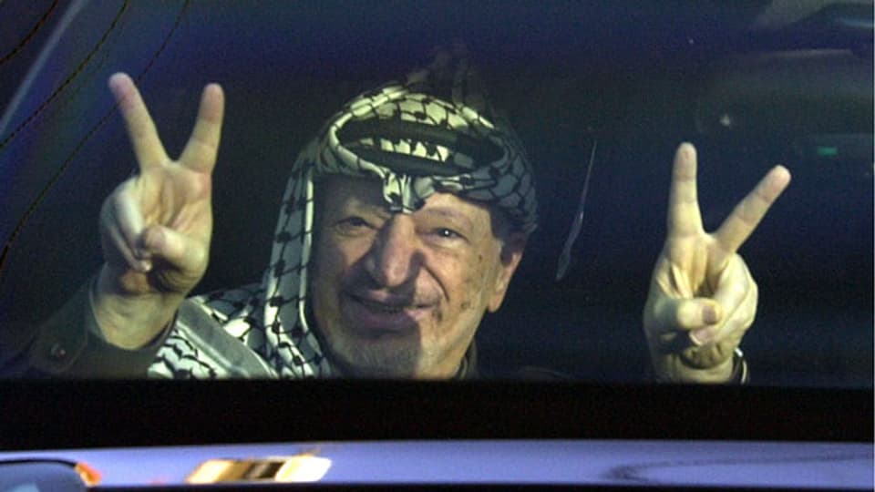  Der Palästinenser-Führer Yasser Arafat blickt aus seinem Auto und macht das Victory-Zeichen in der Stadt Ramallah im Februar 2002.