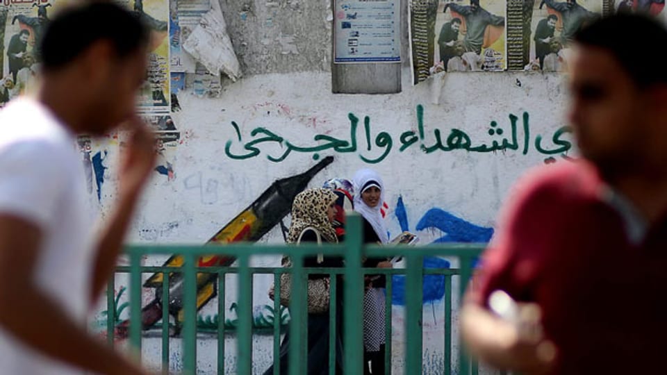 Jugendliche Palästinenser schlendern an einem Porträt von Netanyahu vorbe