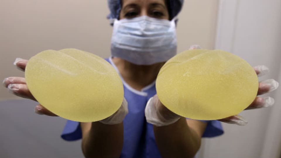 Krankenschwester zeigt defekte französische Brustimplantate.