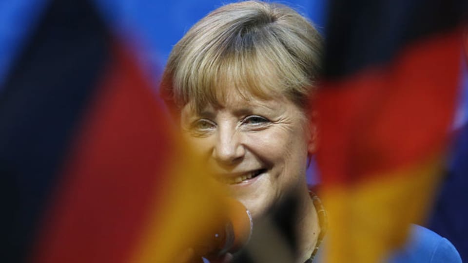 Die deutsche Bundeskanzlerin Angela Merkel hinter den deutschen Fahnen auf der Parteizentrale in Berlin am 22. September 2013.
