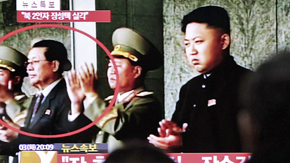 Nordkoreanische Fernseh-News: Rechts Kim Jong Un, im roten Kreis links sein Onkel Jang Song Thaek.