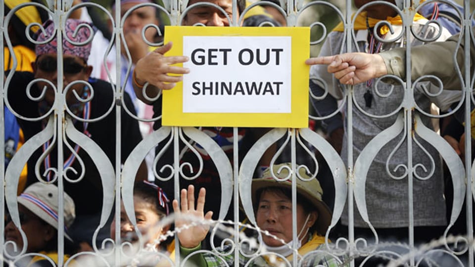 Anti-Regierungs-Demonstranten mit einem ein Plakat hinter einem Zaun am Regierungsgebäude in Bangkok am 9. Dezember 2013.