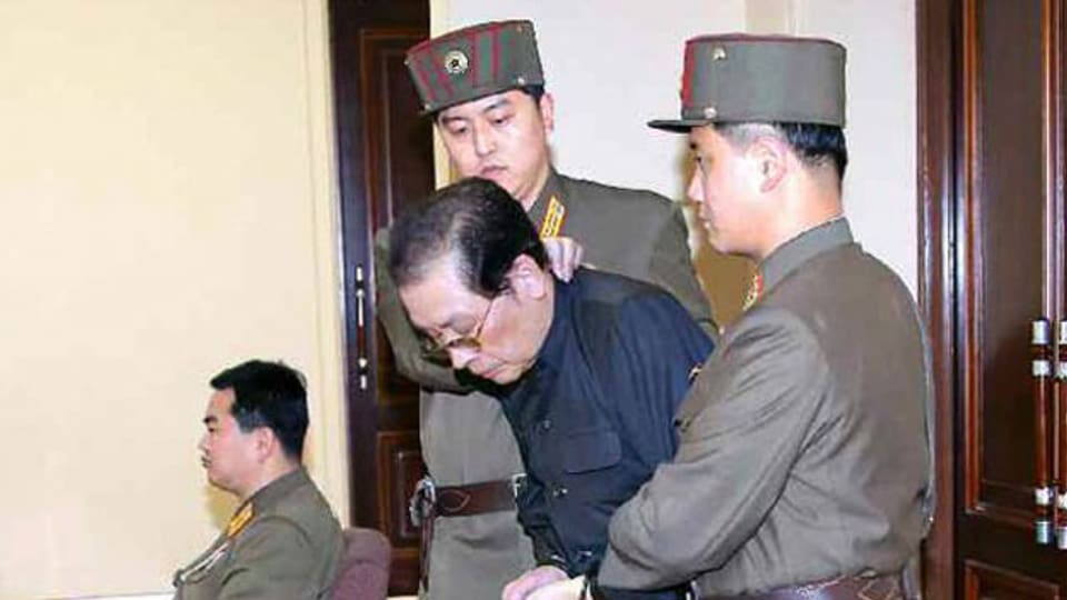 Chang Song Taek wird mit gefesselten Händen wird von zwei Uniformierten in den Gerichtssaal geführt.
