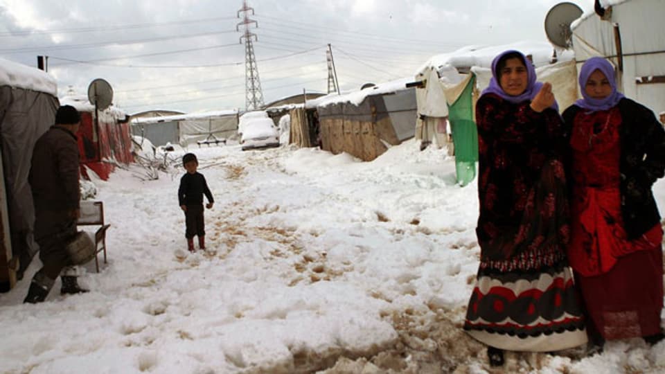 Syrische Flüchtlingsfrauen stehen vor ihrem Zelt in einem syrischen Flüchtlingslager in Al-Marj Dorf,  im libanesischen Bekaa-Tal östlich, am 10. Januar 2013.  Sie leiden nach einem heftigen Schneesturm unter Kälte und Nahrungsmittelknappheit .