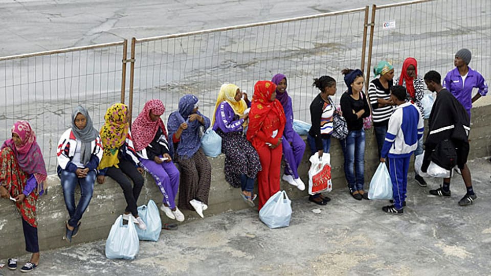 Eine Gruppe Flüchtlinge wartet in Lampedusa auf den Weitertransport in ein Flüchtlingscamp auf dem italienischen Festland.