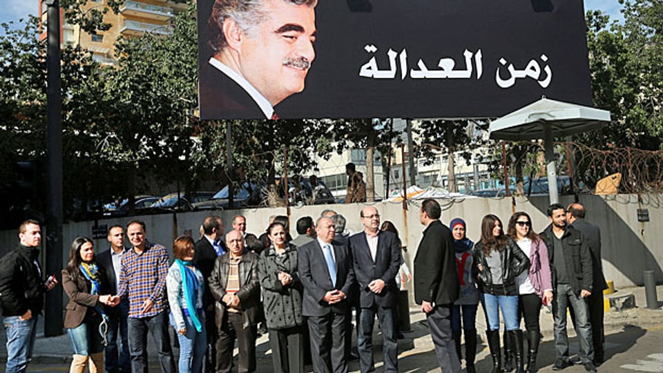 «Zeit für Gerechtigkeit» steht neben dem Portrait Rafik Hariris  auf der riesigen Werbetafel in Beirut. Darunter haben sich AnhängerInnen Rafik Hariris versammelt.