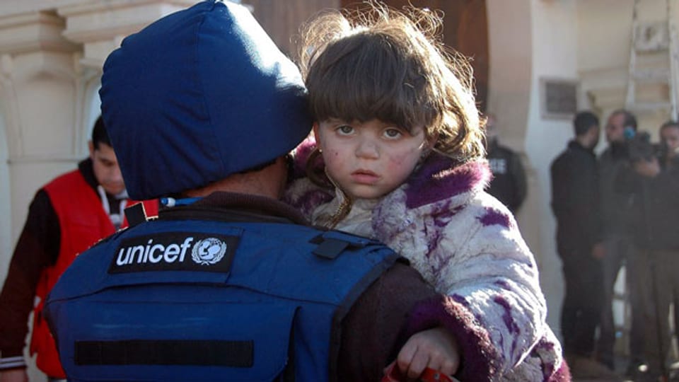 Ein Unicef-Mitglied evakuiert ein Kind aus der belagerten Altstadt von Homs im Zentrum von Syrien. Nun stoppt die Uno die Hilfsmission.