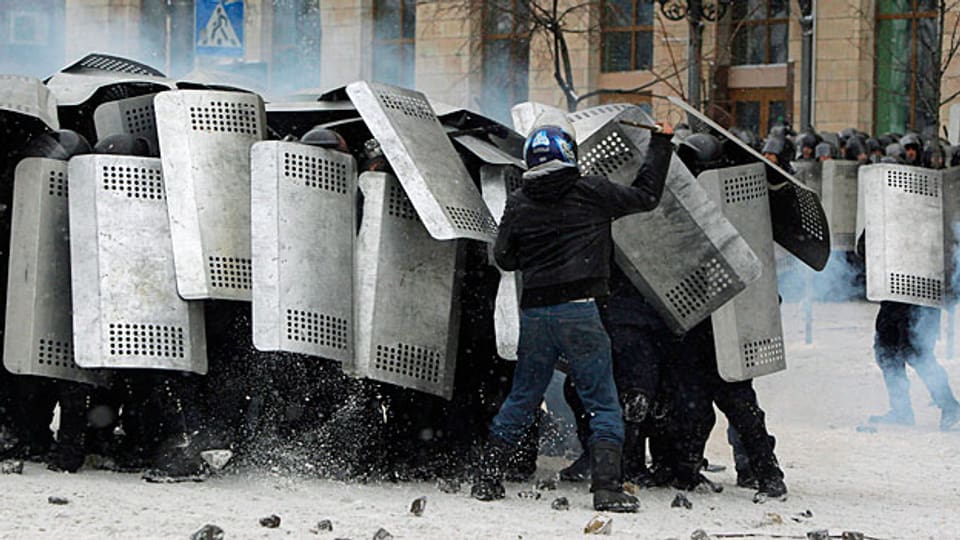 Einer der pro-europäischen Protestierenden attackiert in Kiew die Polizei.