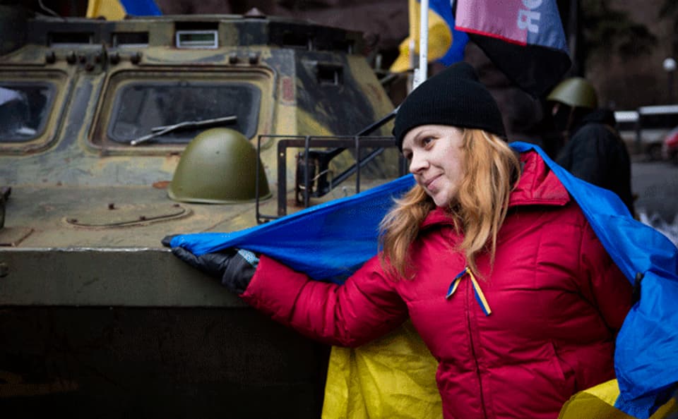 eine Demonstrantin in Kiew vor einem Panzer