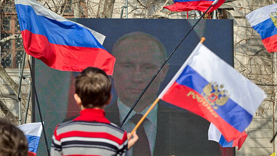 Russinnen und Russen hören der Rede ihres Präsidenten zu.