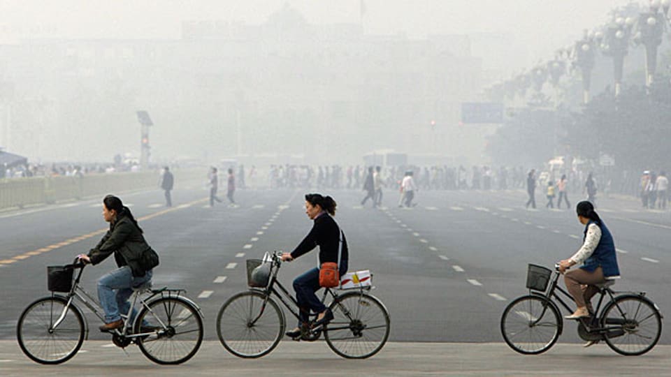 Pekingerinnen radeln durch den Smog der chineischen Hauptstadt.