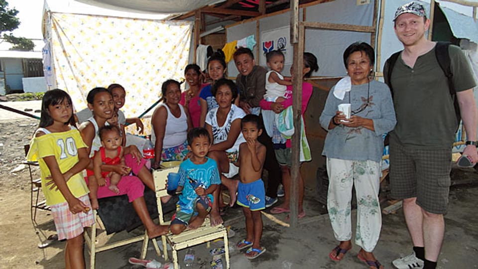 Am rechten Bildrand SRF-Reporter Tobias Fässler in Tacloban, neben ihm die Philippina Estrella mit Kindern, Enkeln und Nachbarn