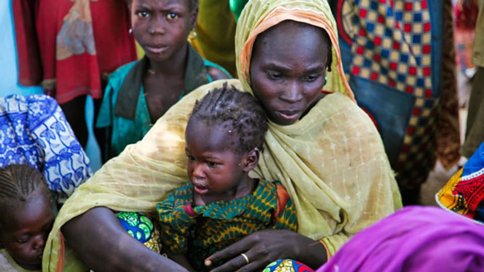 Eine Mutter und ihr Kind sitzen mit anderen Familien in einem Lager für Binnenvertriebene in der Nähe ihres Dorfes in Dougi, Kamerun, 24. Oktober 2013.