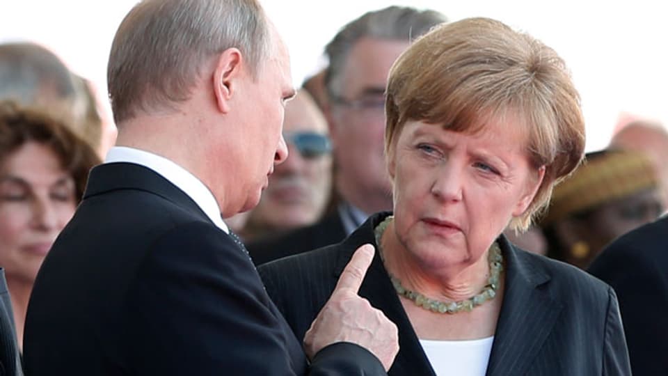 Der russische Präsident Wladimir Putin im Gespräch mit Bundeskanzlerin Angela Merkel am 6. Juni an der 70. D-Day Gedenkfeier in Ouistreham, Frankreich.