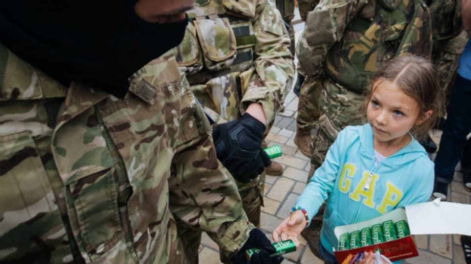 Ein Mädchen übergibt einem ukrainischen Soldaten in Kiev ein Geschenk.