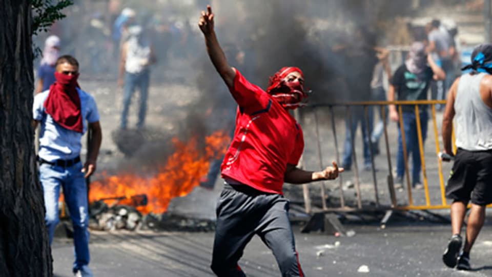 Ein Palästinenser wirft einen Stein bei Zusammenstössen mit der israelischen Polizei in der Nähe von Ost-Jerusalem am  4. Juli 2014.
