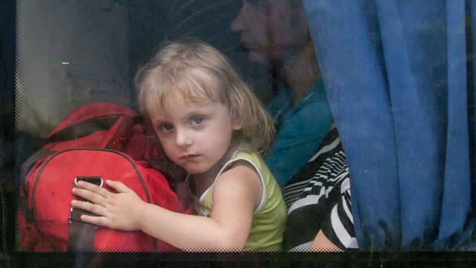 Ein Mädchen schaut aus einem Busfenster, während es mit seinen Eltern die Stadt Slovyansk in der Ostukraine verlässt.