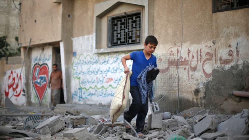 Ein palästinensischer Junge trägt seine Habseligkeiten aus den Trümmern eines Hauses, welches bei einem israelischen Luftangriff in Gaza-Stadt am 15. Juli 2014 zerstört wurde.