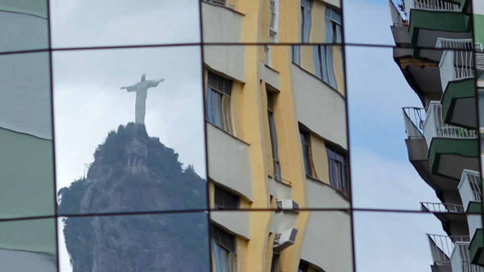 Die Christus-Statue spiegelt sich in der Glasfassade eines Gebäudes in Rio de Janeiro.