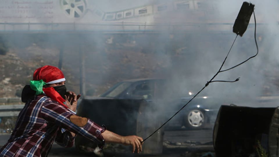 Ein maskierter palästinensischer Demonstrant wirft Steine auf israelische Soldaten während einer Protestaktion gegen die israelische Offensive im Gazastreifen am 18. Juli.