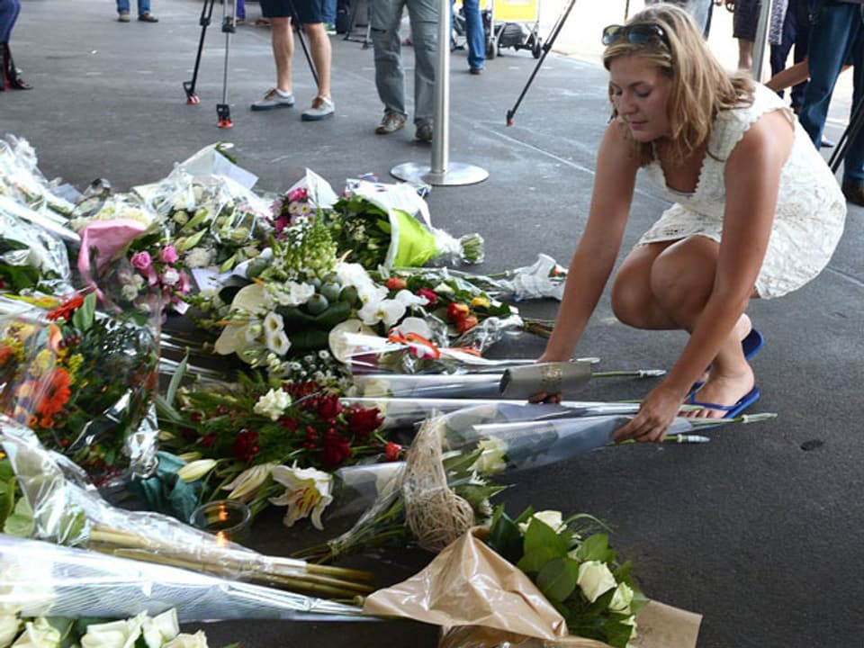 Eine Angehörige legt Blumen beim Flugplatz Schipol in Amsterdam niede