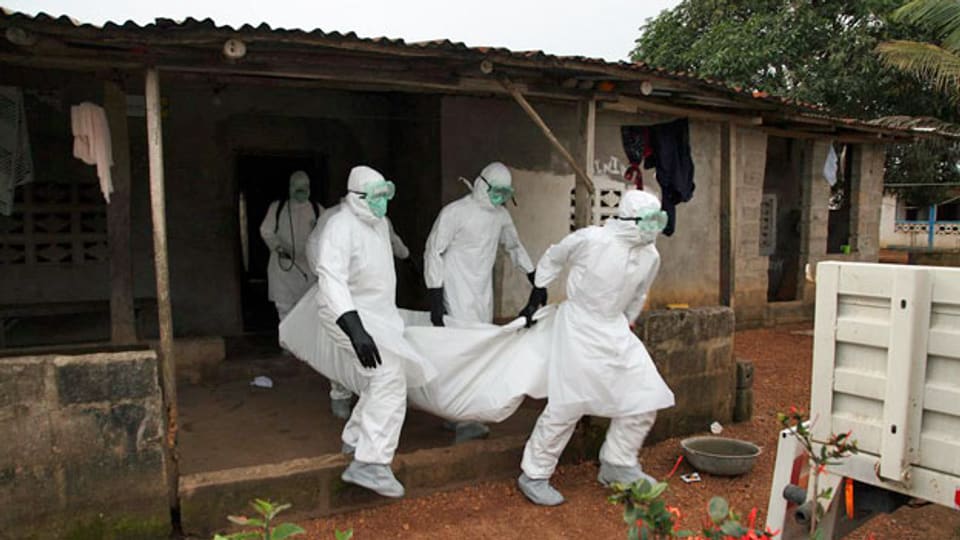 Krankenpfleger in Liberia tragen den Leichnam eines Opfers der Ebola-Epidemie aus einem Haus.