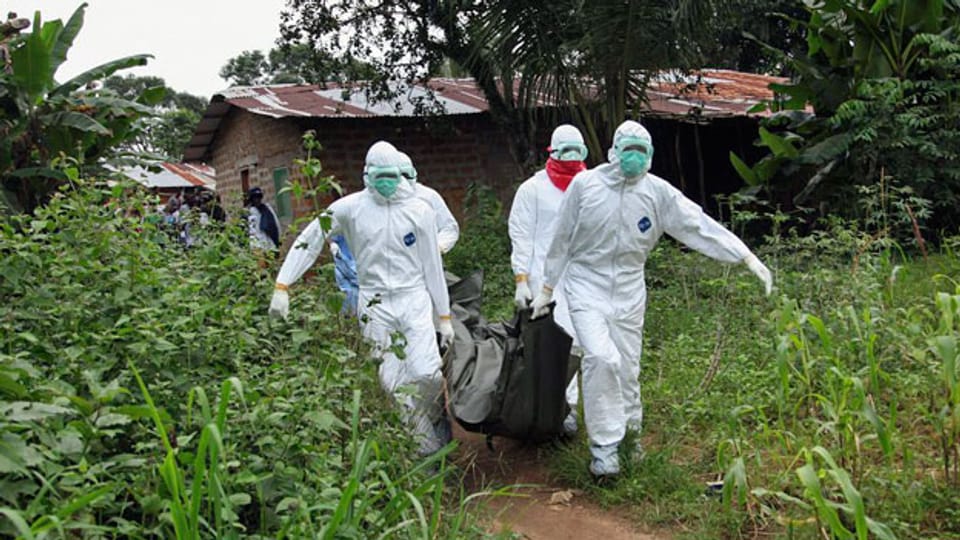 Krankenpfleger tragen den Leichnam eines Ebola-Opfers aus einem Haus.
