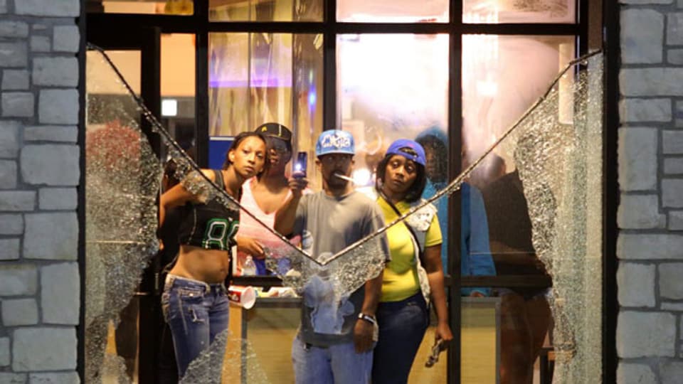 Anwohner schauen durch ein zerbrochenes Fenster in Ferguson, Missouri, USA.