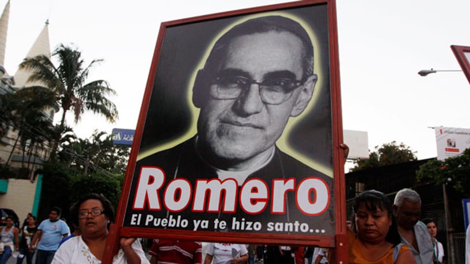 Menschen tragen ein Schild mit einem Bild von Erzbischof Oscar Romero während einer Gedenkfeier in San Salvador.