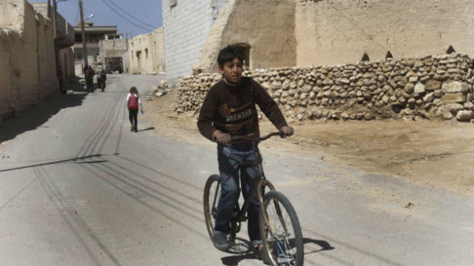 Junge fährt Velo in syrischer Kleinstadt.