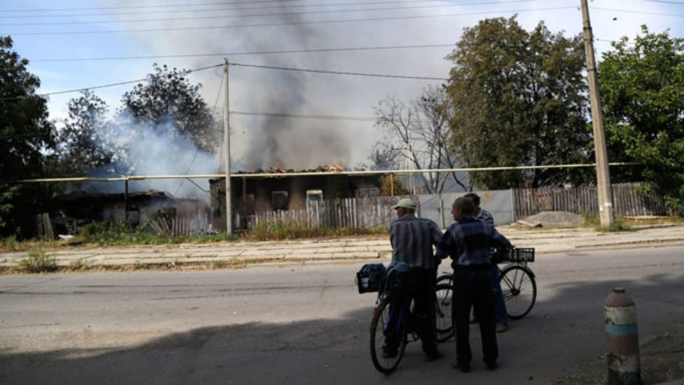 Ukrainer betrachten ein beschossenes Haus in der Nähe von Donezk.