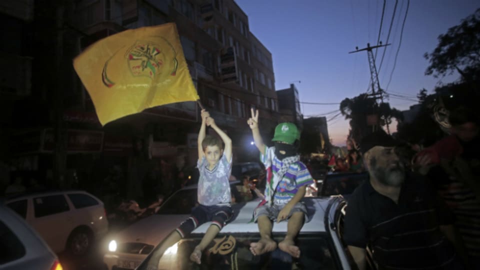 Zwei palästinensische Kinder sitzen auf einem Autodach - eines davon hat eine Fatah-Flagge in der Hand.