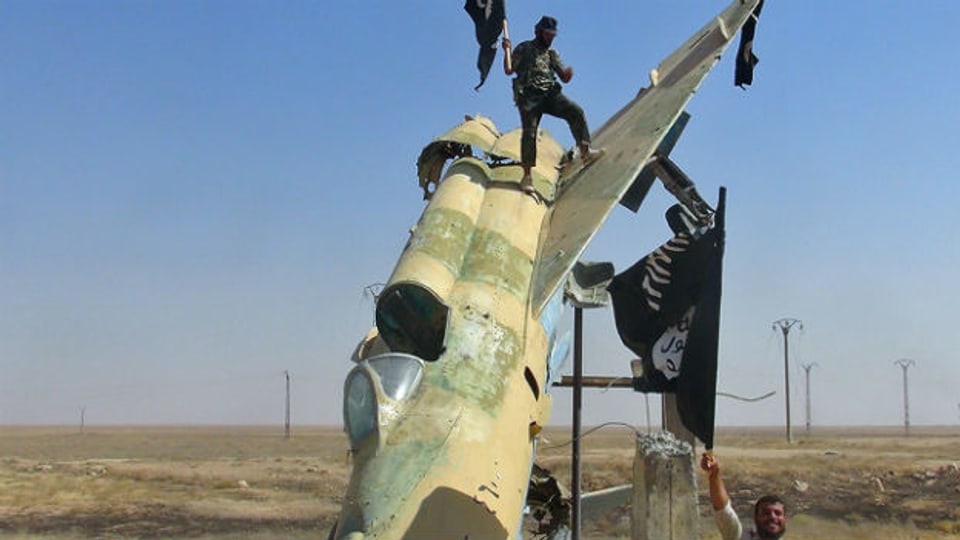 IS-Kämpfer vor einem zerstörten syrischen Flugzeug in der Stadt Raqqa im Norden des Landes (undatierte Aufnahme).
