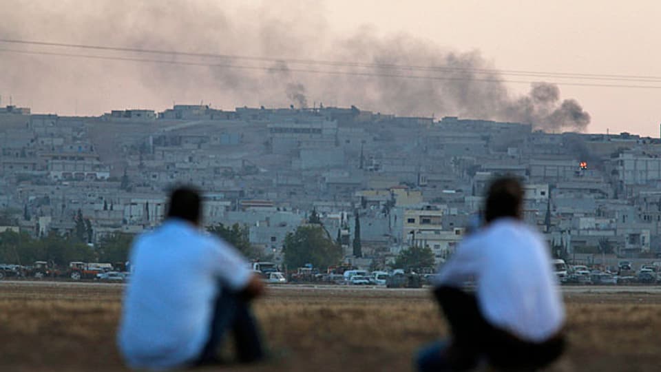 Zwei Kurden schauen von Suruc aus über die Grenze auf die kurdisch-syrische Stadt Kobane.